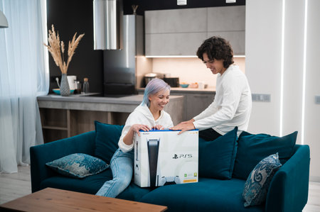 Happy young couple unpacking brand new gaming console Sony Playstation 5 at home. Moscow - November 28 2020.のeditorial素材