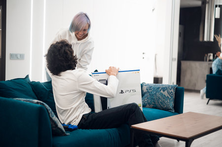 Happy excited woman comes home to make a surprise for her boyfriend with a brand new Sony PlayStation 5 gaming console she bought for christmas. Moscow - November 28 2020のeditorial素材