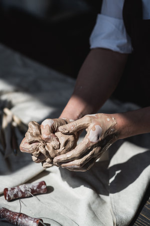 Womans hands wet and dirty after working with clay in a pottery studioの写真素材
