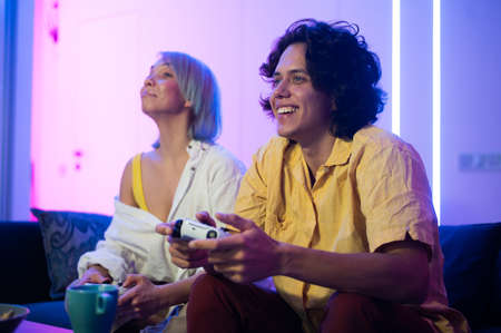 Photo of young couple playing video games at home at nightの写真素材