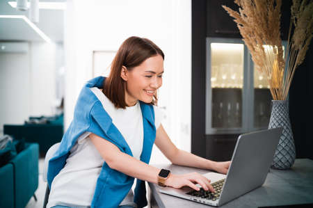 Woman on remote work or online education, using laptop computer, making notes, indoors at home. Online business, young professional at workplace. Working from home.の写真素材