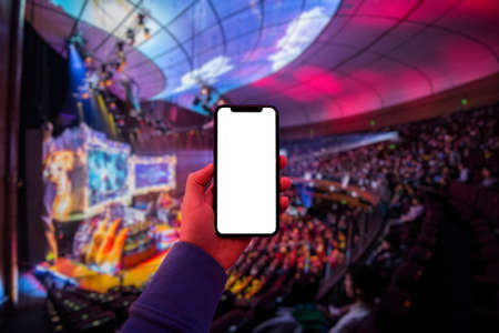 Mans hand using digital application on the mobile smart phone at esport event at big arena. Blank screen with copy space.の写真素材