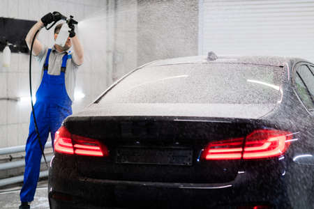 Worker covering automobile with foam at car wash.の写真素材