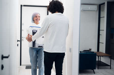 Woman surprises her brother with a next gen Sony playstation 5 console, online shopping present, modern video game device for cyber sport. Moscow - November 28 2020.のeditorial素材