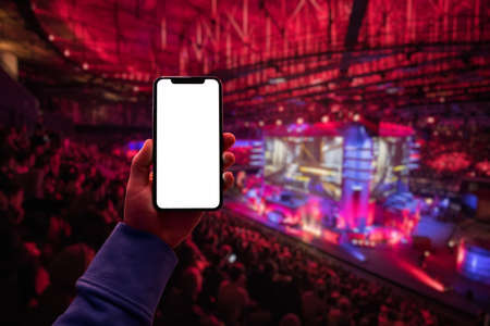 Mans hand using digital application on the mobile smart phone at esport event at big arena. Blank screen with copy space.の写真素材