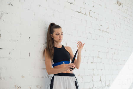 A pretty young athlete wraps a boxing bandage around her arm before trainingの写真素材