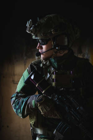 Front view close up of caucasian soldier with a rifle stand guard securing territory looking around.の写真素材