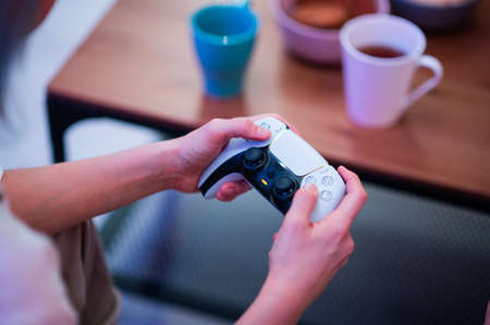 Girl using new Sony Playstation 5 DualSense wireless controller which offers immersive haptic feedback, dynamic adaptive triggers and a built-in microphone. Moscow - November 28 2020.のeditorial素材