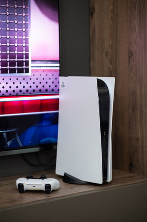 The brand new Sony PlayStation 5 gaming console with DualSense controller near tv screen at home...