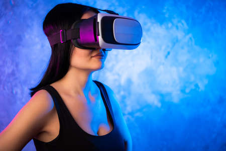 Excited latinn girl in a VR glasses surprised with what she saw. She is touchinmg sonmething and express the emotions from this experienceの写真素材