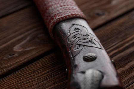 A wooden handle of an ax on a brown wooden background