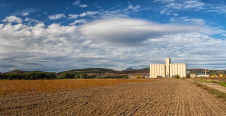 Landscape with field and silo, hills and blue sky with white cloudsの写真素材