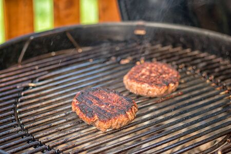 grilled meat - two burnt burgers on an outdoor grillの写真素材