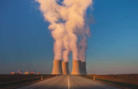 Temelin, Czech republic - 02 28 2021: Nuclear Power Plant, Steaming cooling towers in the landscape at sunset, road leading to factory in foregroundのeditorial素材