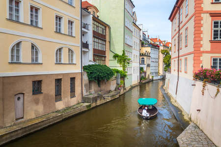 Certovka, cruise boat with tourists sailing between buildings on water canal in Lesser Town, Prague, Czech Republicのeditorial素材