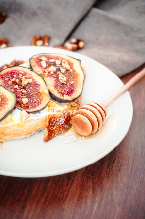 Ange view spelt sourdough toast with feta cheese spread, fresh figs with honey, and raw walnut. Vintage wooden table, coarse cloth burlap, rustic style.の写真素材