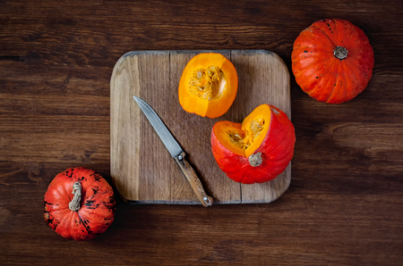 Sliced and whole pumpkins on cutting board with knife on wooden background. Top view in rustic style. Flatlayの写真素材