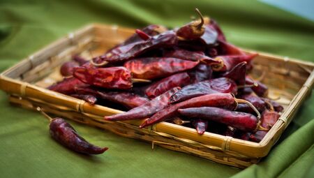 Dried red peppers are lying in a heap, glitering with different shades of redの写真素材