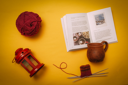 Hygge flat lay with cup, book, knitting needles and tangle, candlestick. Flat lay on yellow backgroundの写真素材