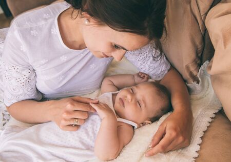 Beautiful young mom near sleeping 3 months baby.