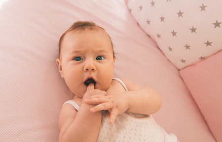 Close-up portrait of a cute baby on the bed in her room.の写真素材