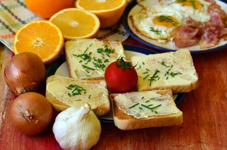 Rustic breakfast - roasted bread with butter and chives, fried eggs and bacon.の写真素材