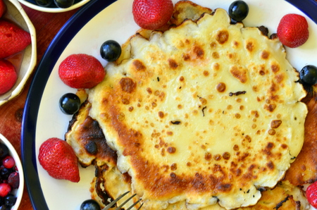 Yummy crepes with strawberries and huckleberries on wooden background