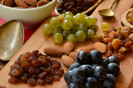 Various raisins, vine berries and almonds on chopping boardの写真素材