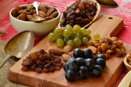 Various raisins, vine berries and almonds on chopping boardの写真素材