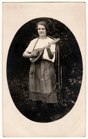 GERMANY - 1930s: Vintage photo shows a woman plays mandolin outdoors. Photo is oval shape. Black &...