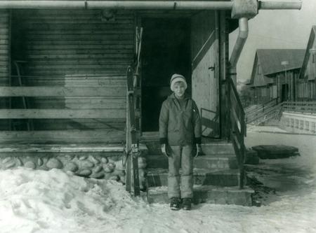 THE CZECHOSLOVAK SOCIALIST REPUBLIC - CIRCA 1980s: Retro photo shows a young boy in winter time. Boy stands in front of chalet with skis. Vintage black & white photography.のeditorial素材