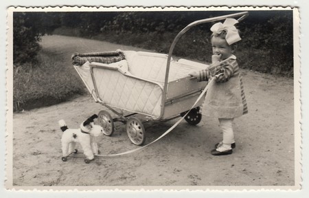 THE CZECHOSLOVAK REPUBLIC, CIRCA 1942: A small girl with dog toy and pram (baby carriage), circa 1942.のeditorial素材