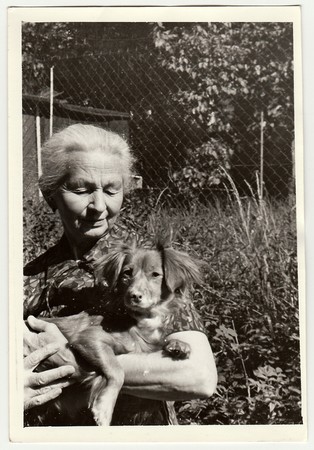 USSR - CIRCA 1980s: Vintage photo shows old woman cradles dog (dachshund).のeditorial素材