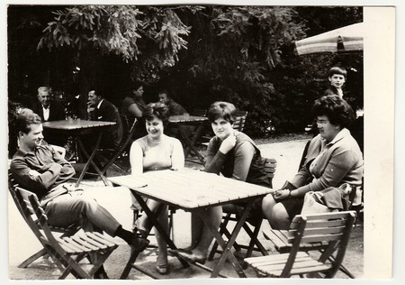 THE CZECHOSLOVAK SOCIALIST REPUBLIC - CIRCA 1960s: Vintage photo shows group of people sit at the garden restaurant.のeditorial素材