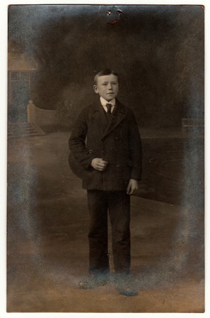 THE CZECHOSLOVAK REPUBLIC - CIRCA 1920s: Vintage photo shows boy wears suit and tie. Antique black & white photo taken outdoors. On top of the image is imprint of drawing pin. Photo has dark tint.のeditorial素材
