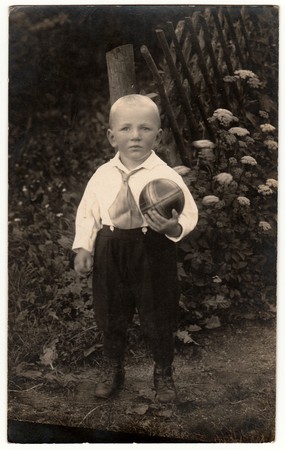 THE CZECHOSLOVAK REPUBLIC - CIRCA 1930s: Vintage photo shows a small boy with ball poses outdoors. Black & white antique photo.のeditorial素材
