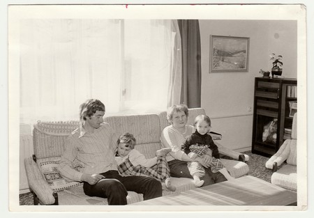 THE CZECHOSLOVAK SOCIALIST REPUBLIC - CIRCA 1980s: Vintage photo shows parents with their children in the living room. Antique black & white photo.のeditorial素材