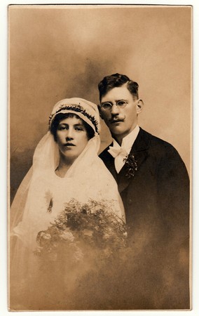 THE CZECHOSLOVAK  REPUBLIC - CIRCA 1930s: Vintage photo of newlyweds. Bride wears a veil and holds wedding bouquet. Groom wears black suit and white bow tie. Black & white antique studio portraitのeditorial素材