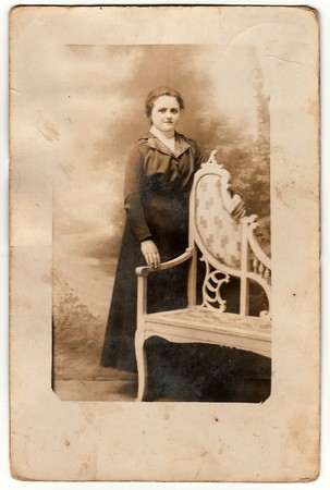 THE CZECHOSLOVAK REPUBLIC - CIRCA 1920s: Vintage photo shows young woman poses next to historic carved bench. Black & white antique photography.のeditorial素材