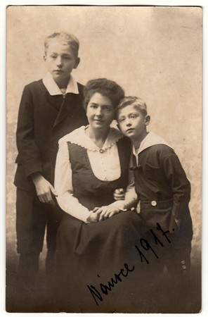 PRAGUE, AUSTRIA-HUNGARY - CHRISTMAS, 1917: Vintage photo shows mother with children (boys). Black & white antique photography.のeditorial素材