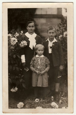 GERMANY - CIRCA 1940s: Vintage photo shows young woman with children (boy and girl) pose in the garden. Black & white antique photography.のeditorial素材