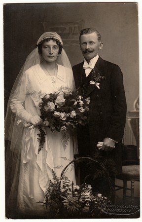 CHRASTAVA (KRATZAU), THE CZECHOSLOVAK  REPUBLIC - CIRCA 1930s: Vintage photo of newlyweds. Bride wears a veil and holds wedding bouquet. Black & white antique studio portrait.のeditorial素材