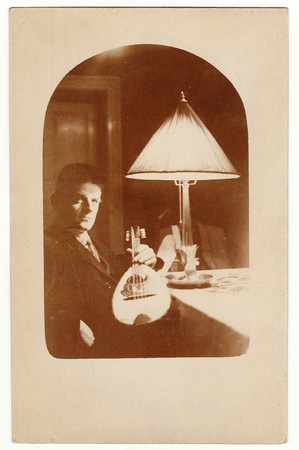 CHEMNITZ, GERMANY - MAY 10, 1927: Vintage photo shows man with the mandolin. He sits at the table....