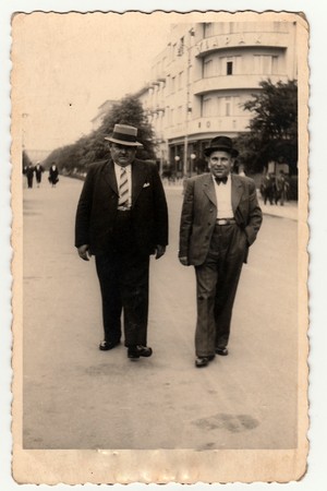 LAZNE PODEBRADY, THE CZECHOSLOVAK REPUBLIC - CIRCA 1940s: Vintage photo shows the elegant men at the spa resort. They wear hats and slack suits. Colonnade is on background.のeditorial素材