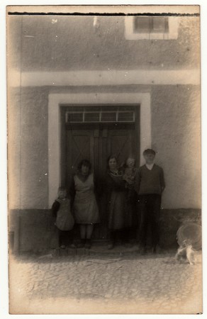 THE CZECHOSLOVAK REPUBLIC - CIRCA 1920s: Vintage photo shows a rural family in front of house. Photography contains slight blurriness.のeditorial素材