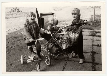 THE CZECHOSLOVAK SOCIALIST REPUBLIC - CIRCA 1970s: Retro photo shows children who play with pram and tricycle.  Black & white vintage photography.のeditorial素材