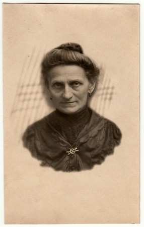 GERMANY - CIRCA 1930s: Vintage photo shows elderly woman - portrait in a photography studio. Woman with Edwardian hairstyle. Retro black & white studio photography with sepia effect. Head is drawn to body.のeditorial素材