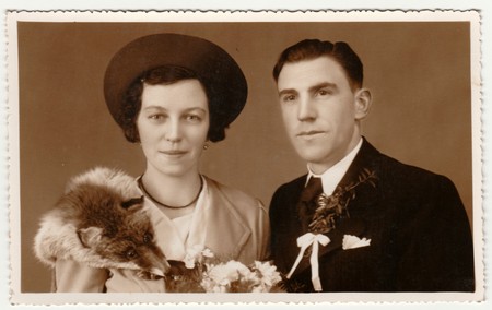 PRAGUE, THE CZECHOSLOVAK  REPUBLIC - CIRCA 1940s: Vintage photo shows newlyweds. Wedding ceremony - bride and groom. Bride wears fox scarf. Retro black & white photography with sepia effect.のeditorial素材