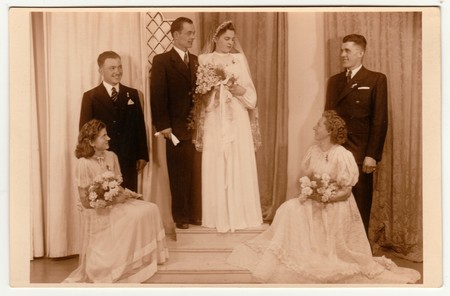 PRAGUE, THE CZECHOSLOVAK REPUBLIC - APRIL 18, 1942: Vintage photo shows newlyweds and bridesmaids. Retro black & white photography with sepia effect.のeditorial素材