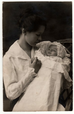 GERMANY - APRIL 25, 1918: Vintage photo shows woman with baby (newborn) in swaddling clothes. Retro black & white studio photography.のeditorial素材